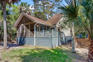 a small house with a porch and a palm tree at Artsea Phartsea in Edisto Beach