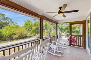 a porch with white chairs and a ceiling fan at Cupid's Nest in Edisto Beach