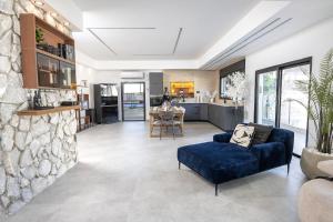 a living room with a blue couch and a stone wall at פלואלס - וילת יוקרה עם 4 חדרי שינה ובריכה מחוממת וגקוזי in Shahar