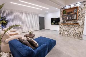 a living room with a blue couch and a stone wall at פלואלס - וילת יוקרה עם 4 חדרי שינה ובריכה מחוממת וגקוזי in Shahar