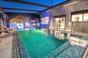 a large swimming pool in a building with blue water at פלואלס - וילת יוקרה עם 4 חדרי שינה ובריכה מחוממת וגקוזי in Shahar