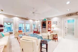 a living room with white furniture and a ceiling fan at Slow Drift in Edisto Beach