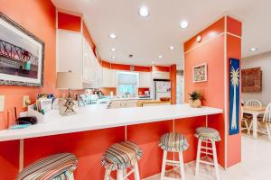 a kitchen with orange walls and bar stools at Slow Drift in Edisto Beach