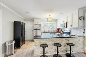 a kitchen with white cabinets and black appliances with bar stools at Heaven on Harrelson in Edisto Beach