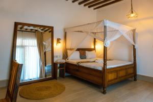 a bedroom with a canopy bed and a mirror at Jaje Paje Villa in Paje