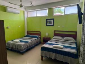two beds in a room with green walls and windows at JAARR Alojamientos in Pucallpa