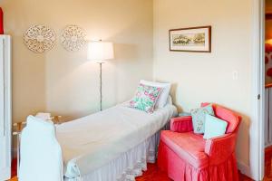 a bedroom with a bed and a red chair at Pink Bird Cottage in Edisto Beach +19 photos