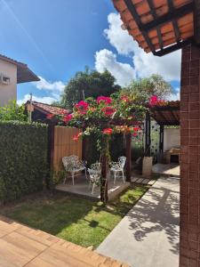 a garden with a pergola with pink flowers and chairs at Casa em Salinas in Salinópolis