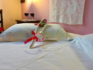 a bow on top of a bed with two glasses of wine at Varosi Guesthouse in Edessa