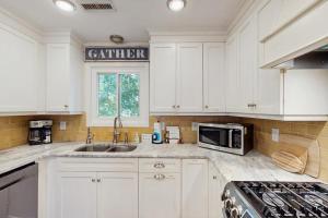 a white kitchen with a sink and a microwave at Summer House in Edisto Beach