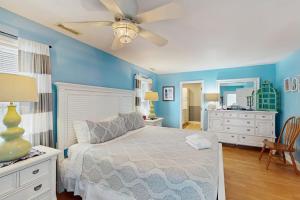 a bedroom with blue walls and a bed with a ceiling fan at Summer House in Edisto Beach +20 photos