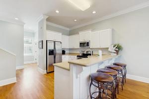 a kitchen with white cabinets and bar stools at King Cotton Villa 17 in Edisto Beach +16 photos