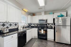 a kitchen with white cabinets and black appliances at Sunrise, Sunset in Edisto Beach