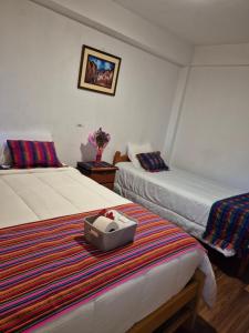 a hotel room with two beds and a suitcase on a rug at VittoriaHouse in Ollantaytambo