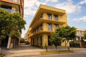 a yellow building with trees in front of it at Sunny Hotel in Kobuleti