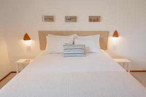 a white bed with a blue and white pillow on it at Casa Aia - Hospedagem de Charme na Atalaia in Aracaju