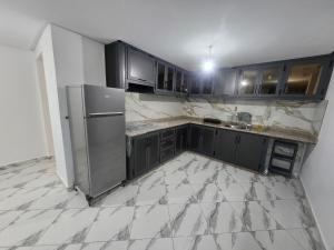 a kitchen with black cabinets and a stainless steel refrigerator at Aerport arwi accom in Nador Airport