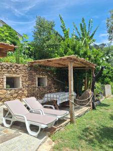 two lounge chairs and a table and a stone wall at Casa dos Pobres in Castro Daire