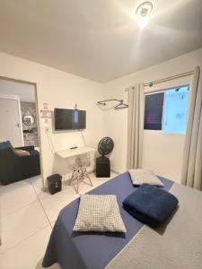 a bedroom with two beds and a desk and a television at Cantinho Aconchegante - Apartamento Completo in Bayeux +11 photos