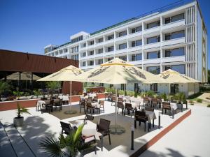 an outdoor patio with tables and chairs and umbrellas at Hotel Belvedere in Eforie Nord
