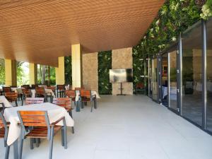 a restaurant with tables and chairs and a flat screen tv at Hotel Belvedere in Eforie Nord