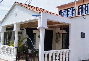 a white house with a porch and a white fence at Casa Vacacional Algarrobos in Girardot