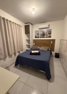 a bedroom with a bed with a blue comforter at Cantinho Aconchegante - Apartamento Completo in Bayeux