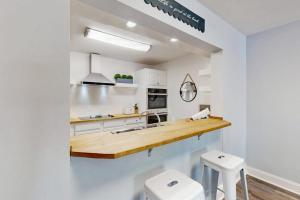 a kitchen with white cabinets and a counter with two stools at Xanadu D8 in Hilton Head Island