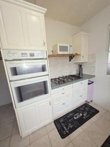 a kitchen with white cabinets and a stove top oven at Gloria's Hideaway in Christ Church