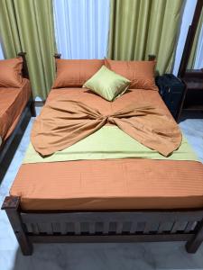a bed with orange sheets and a pillow on it at Samadi hotel and resort in Kekirawa