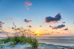 a sunset on a beach with sand and the ocean at Windsor Court North 4504 in Hilton Head Island