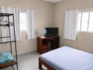 a bedroom with a bed and a desk with a fan at Studio aconchegante perto dos eventos! in Garanhuns