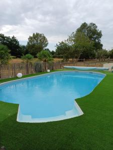 a large blue swimming pool on a green lawn at La Tiny des Prés in LʼAbsie
