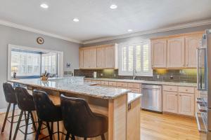 a kitchen with wooden cabinets and a large island with bar stools at Why Knot? in Edisto Island +76 photos