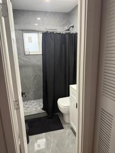 a bathroom with a black shower curtain and a toilet at Casa relax in North Miami Beach