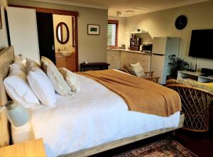 a bedroom with a large bed and a kitchen at Brushwood Studio - Eco Hideaway - Denmark WA in Denmark