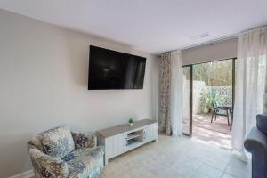 a living room with a chair and a television on the wall at Beach Club Bungalow in Hilton Head Island