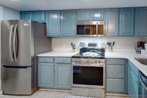 a kitchen with blue cabinets and a stainless steel refrigerator at Beach Club Bungalow in Hilton Head Island +13 photos
