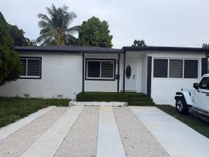 a white house with a car parked in front of it at Casa paz in North Miami Beach