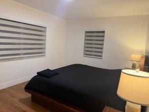 a bedroom with a black bed and two windows at Casa paz in North Miami Beach