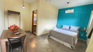 a bedroom with a blue wall and a bed and a table at Pousada Iandara in Pirenópolis +8 photos