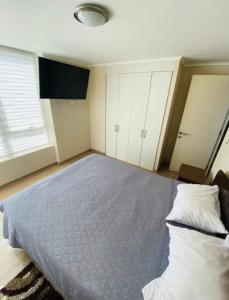 a bedroom with a bed with a blue comforter at Departamento Centro Chillán in Chillán