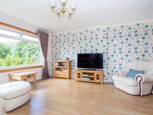 a living room with a couch and a tv at Caledon in Aviemore