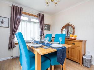 a dining room with a wooden table and blue chairs at Caledon in Aviemore