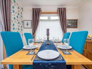 a dining room table with blue chairs and a wooden table with wine glasses at Caledon in Aviemore