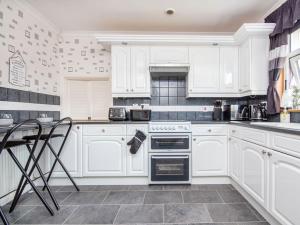 a white kitchen with white cabinets and a stove at Caledon in Aviemore +10 photos