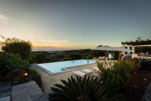 a villa with a swimming pool and an umbrella at Monte da Casa Telhada in Santiago do Cacém