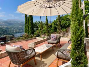 a patio with chairs and a table and an umbrella at Pedacinho de Mundo Douro in Passinhos de Cima