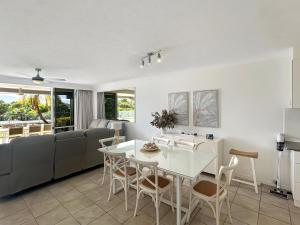 a kitchen and living room with a white table and chairs at Beach Lodges in Hamilton Island