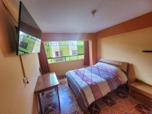 a bedroom with a bed and a tv and a window at Hostal Huagancu in Huari